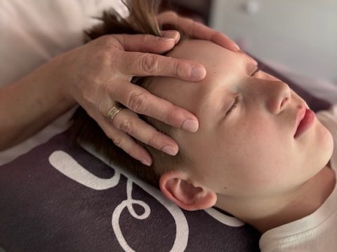 Ein Kind erhält eine sanfte Kopf- und Nackenmassage.